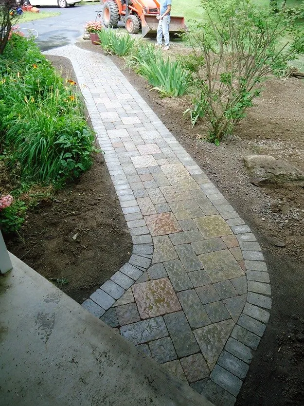 Same front yard after, with a curved paver walkway and new plantings