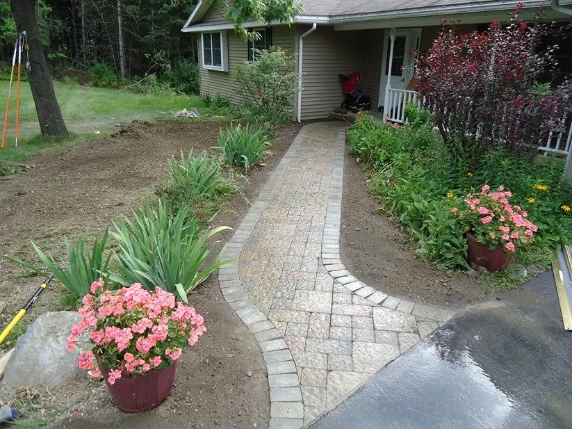 Paver walkway with fresh garden beds leading to a front porch