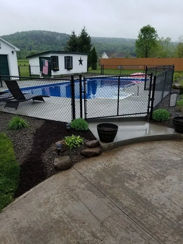 Mulched garden beds and stone edging beside a pool